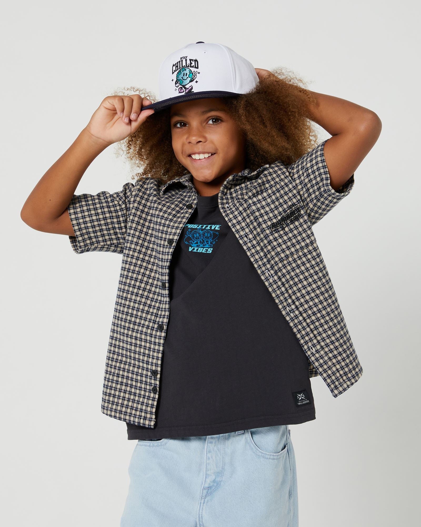 Boys Alphabet Soup's Kids Check It Short Sleeve Shirt is made from 100% cotton and features a curved hemline, button through placket, and open chest pocket. Ideal for any drop-in, with yarn check fabric and embroidered art.