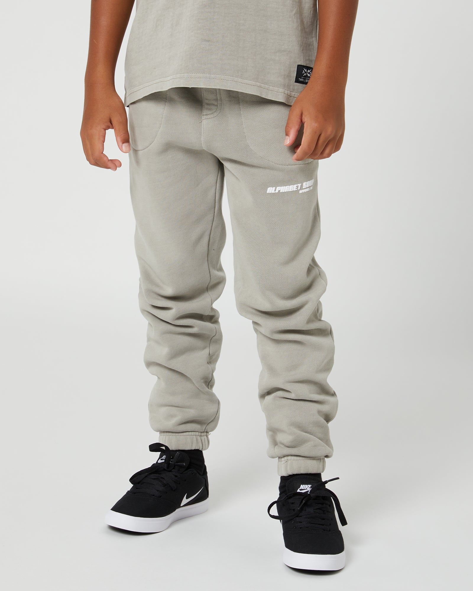 Teen Boys San Clemente Trackpant in Concrete by Alphabet Soup featuring a vintage garment dye wash, heavy brushed back fleece, and puff print design on the front leg create the perfect blend of comfort and style. Elasticated waist and ribbed cuff ankles ensure an all-day fit.