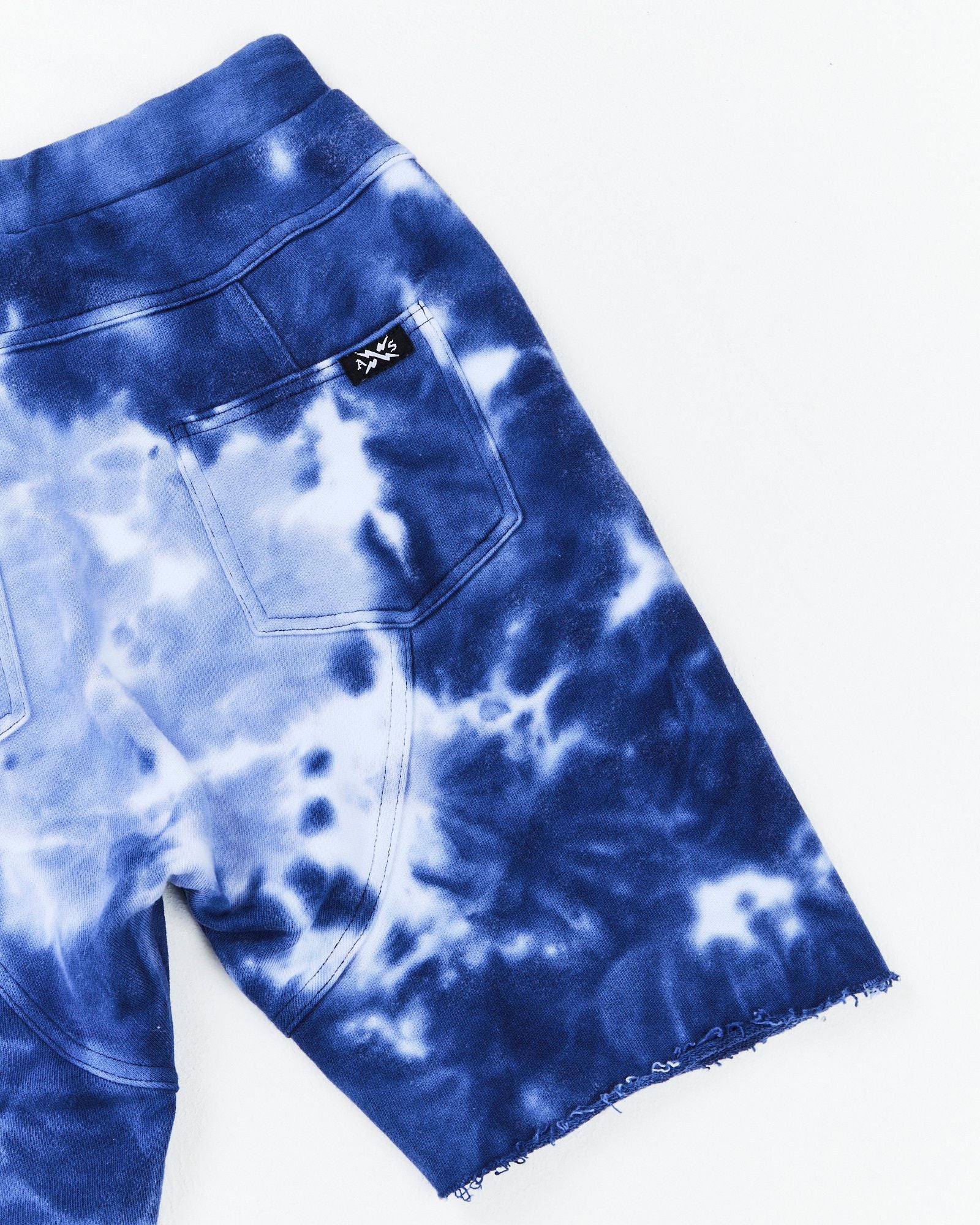 Alphabet Soup's Teen Cloud Surfer Shorts for boys aged 8-19. 100% French Terry fabric and blue cloud marble dye ensures comfort and style. Elasticated waist, adjustable drawcord, faux fly and raw hem. Back panel detail and embroidery on front pocket.