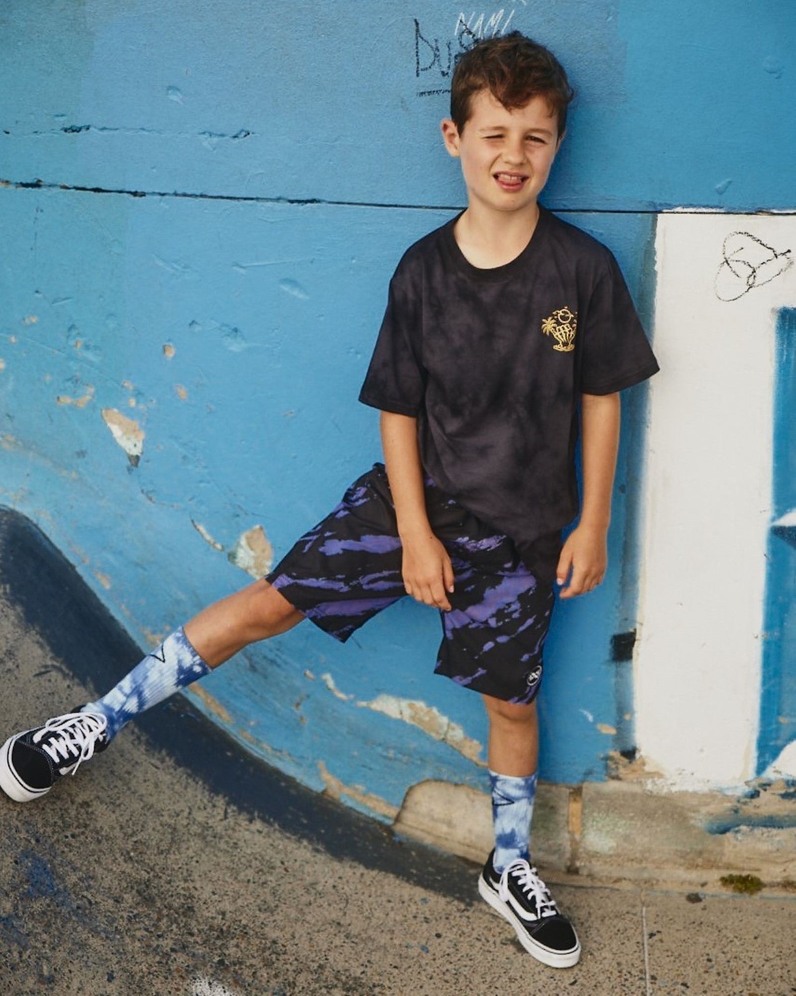 Alphabet Soup's Kids Night Howler Shaka Tee for boys aged 2-7. Featuring 100% black cotton jersey, reg. fit, short sleeves, ribbed neck, two-tone tie dye, shaka print with “Good Times Ahead” on chest & back.