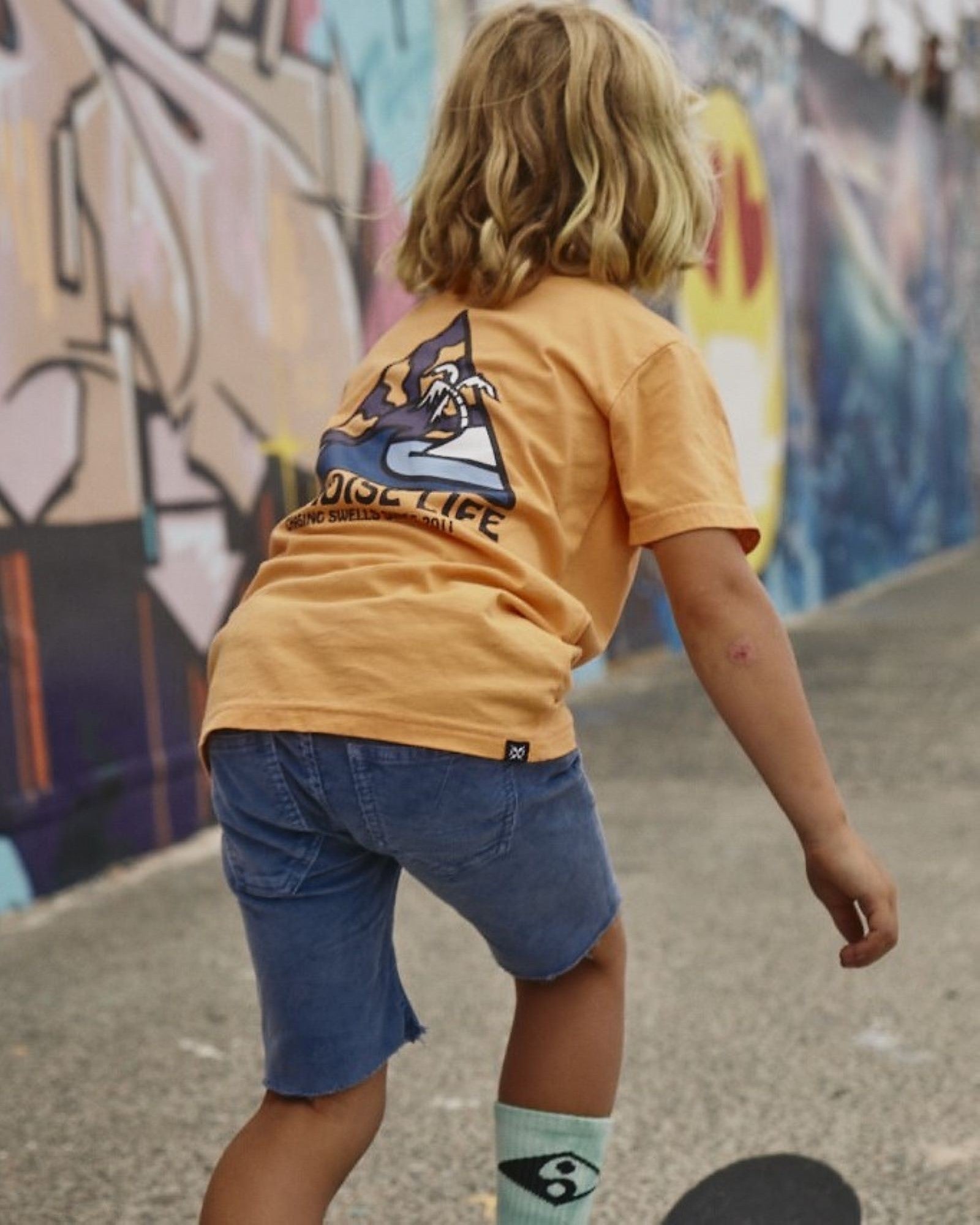 Alphabet Soup's Teen Trusty Cord Shorts for boys aged 8-16.  Crafted with cotton corduroy in blue enzyme wash with stretch, including adjustable waist, raw hem, faux fly, hip & back pockets with bolt embroidery.