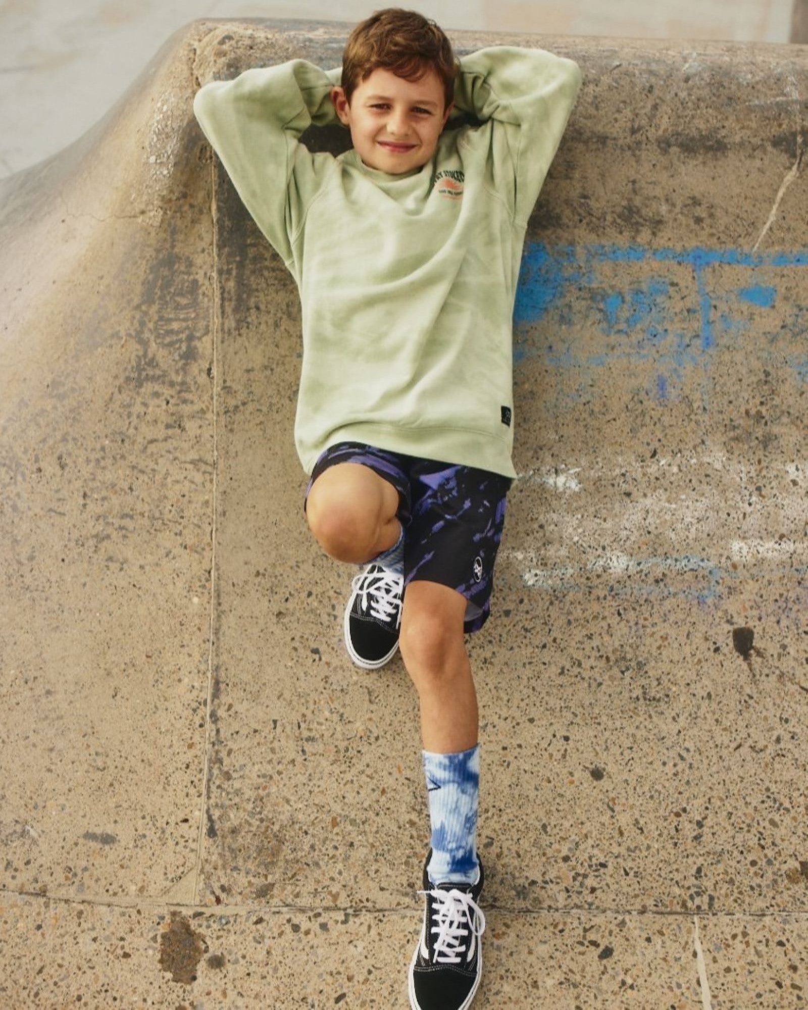 Kids Riptide Boardshorts by Alphabet Soup for boys aged 2-7. Feature an elastic waist, faux fly, diagonal tie purple and black dye, and bold logo patches.
