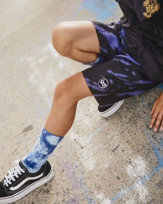 Kids Riptide Boardshorts by Alphabet Soup for boys aged 2-7. Feature an elastic waist, faux fly, diagonal tie purple and black dye, and bold logo patches.